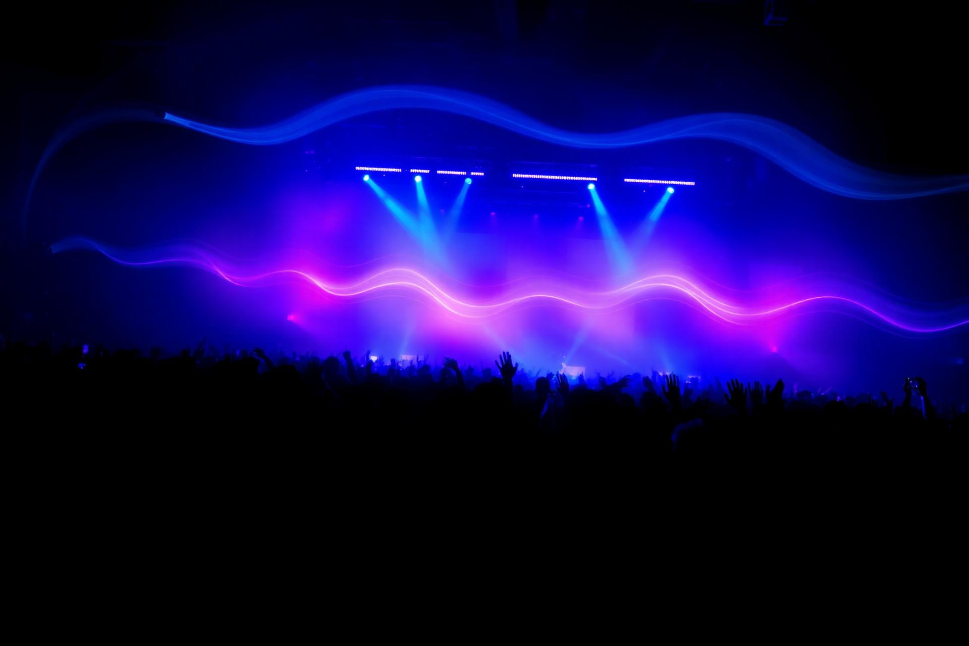 Crowd of concert-goers under electric blue and neon pink stage lights